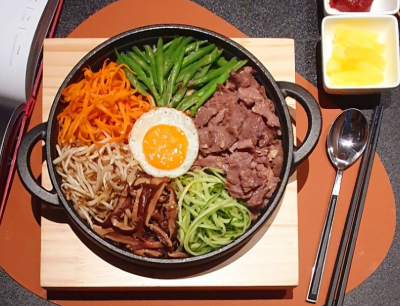 Cơm trộn bò là một món ăn hấp dẫn, nổi bật với sự kết hợp hài hòa giữa nhiều nguyên liệu tươi ngon và màu sắc bắt mắt. Ngay từ cái nhìn đầu tiên, món ăn đã gây ấn tượng với bát cơm đầy đặn, bên trên là những lát thịt bò xào mềm, xen lẫn với các loại rau củ như cà rốt, dưa leo, rau xanh và trứng. Tất cả được sắp xếp gọn gàng, tạo nên một tổng thể vừa đẹp mắt vừa kích thích vị giác. Điểm đặc trưng của cơm trộn bò nằm ở sự đa dạng trong thành phần. Cơm trắng đóng vai trò nền tảng, với hạt cơm dẻo mềm, nóng hổi. Thịt bò được thái mỏng, ướp gia vị vừa phải rồi xào nhanh trên lửa lớn, giữ được độ mềm và vị ngọt tự nhiên. Khi ăn, từng miếng thịt bò thơm lừng, đậm đà kết hợp với cơm tạo nên cảm giác ngon miệng và đầy đủ. Các loại rau củ ăn kèm không chỉ giúp tăng màu sắc mà còn mang lại sự cân bằng cho món ăn. Cà rốt giòn nhẹ, dưa leo mát lành, rau xanh tươi tạo cảm giác thanh mát, giúp giảm độ ngấy của thịt bò. Trứng chiên hoặc trứng lòng đào thường được đặt lên trên, khi trộn đều sẽ tạo nên độ béo ngậy, làm món ăn thêm phần hấp dẫn. Điểm làm nên linh hồn của cơm trộn bò chính là phần nước sốt. Tùy theo cách chế biến, nước sốt có thể mang vị mặn ngọt hoặc cay nhẹ, giúp liên kết tất cả nguyên liệu lại với nhau. Khi trộn đều, cơm, thịt bò và rau củ hòa quyện, tạo nên hương vị đậm đà, phong phú và khó quên. Không chỉ ngon miệng, cơm trộn bò còn cung cấp nhiều giá trị dinh dưỡng. Thịt bò là nguồn protein và sắt dồi dào, giúp tăng cường sức khỏe và năng lượng. Rau củ cung cấp vitamin và chất xơ, hỗ trợ tiêu hóa, trong khi cơm mang lại nguồn tinh bột cần thiết cho cơ thể. Sự kết hợp này giúp món ăn trở nên cân bằng và phù hợp với nhiều đối tượng. Ngoài ra, cơm trộn bò còn mang lại cảm giác tiện lợi và linh hoạt. Món ăn có thể dễ dàng biến tấu với nhiều nguyên liệu khác nhau tùy theo sở thích, từ đó tạo nên những phiên bản riêng biệt nhưng vẫn giữ được nét đặc trưng. Đây là lựa chọn lý tưởng cho những bữa ăn nhanh gọn nhưng vẫn đảm bảo chất lượng. Trong nhịp sống hiện đại, cơm trộn bò ngày càng được ưa chuộng bởi sự ngon miệng, đầy đủ dinh dưỡng và hình thức hấp dẫn. Một bát cơm trộn nóng hổi, đầy màu sắc không chỉ làm no bụng mà còn mang lại cảm giác hài lòng và trọn vẹn. Đây không chỉ là món ăn ngon mà còn thể hiện sự tinh tế trong cách kết hợp nguyên liệu, tạo nên trải nghiệm ẩm thực thú vị cho người thưởng thức.