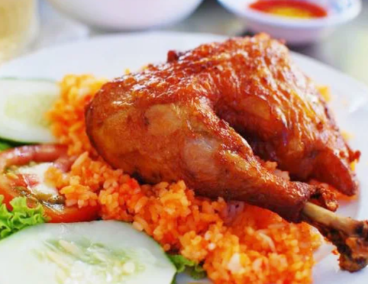 Cơm gà xối mỡ là món ăn hấp dẫn với hương vị đậm đà và vẻ ngoài bắt mắt. Phần cơm vàng óng, tơi xốp, được nấu từ nước luộc gà nên thơm và béo nhẹ. Điểm nổi bật nhất là miếng gà chiên giòn, lớp da vàng rụm, thịt bên trong mềm ngọt, giữ được độ mọng nước. Khi ăn, lớp da giòn tan kết hợp với cơm nóng tạo nên sự hòa quyện hoàn hảo. Món ăn thường được dùng kèm dưa leo, cà chua và rau sống để tăng độ tươi mát, cân bằng vị béo. Nước chấm chua ngọt hoặc xì dầu giúp món ăn thêm phần đậm đà. Không chỉ ngon, cơm gà xối mỡ còn cung cấp nhiều năng lượng, phù hợp cho bữa ăn no lâu. Đây là lựa chọn quen thuộc, được nhiều người yêu thích.