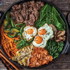 Cơm trộn bò là món ăn hấp dẫn với sự kết hợp hài hòa giữa cơm, thịt bò và nhiều loại rau củ tươi ngon. Bát cơm trắng dẻo mềm được phủ lên trên là thịt bò xào thơm, mềm và đậm vị. Đi kèm là cà rốt, dưa leo, rau xanh giúp tăng màu sắc và tạo cảm giác thanh mát. Trứng chiên hoặc trứng lòng đào thường được thêm vào, tạo độ béo ngậy khi trộn đều. Điểm đặc biệt của món ăn là phần nước sốt đậm đà, giúp các nguyên liệu hòa quyện với nhau, tạo nên hương vị phong phú. Khi thưởng thức, người ăn cảm nhận được sự cân bằng giữa vị ngọt của thịt, vị tươi của rau và vị dẻo của cơm. Không chỉ ngon, cơm trộn bò còn cung cấp đầy đủ dinh dưỡng, phù hợp cho bữa ăn nhanh gọn nhưng vẫn hấp dẫn.